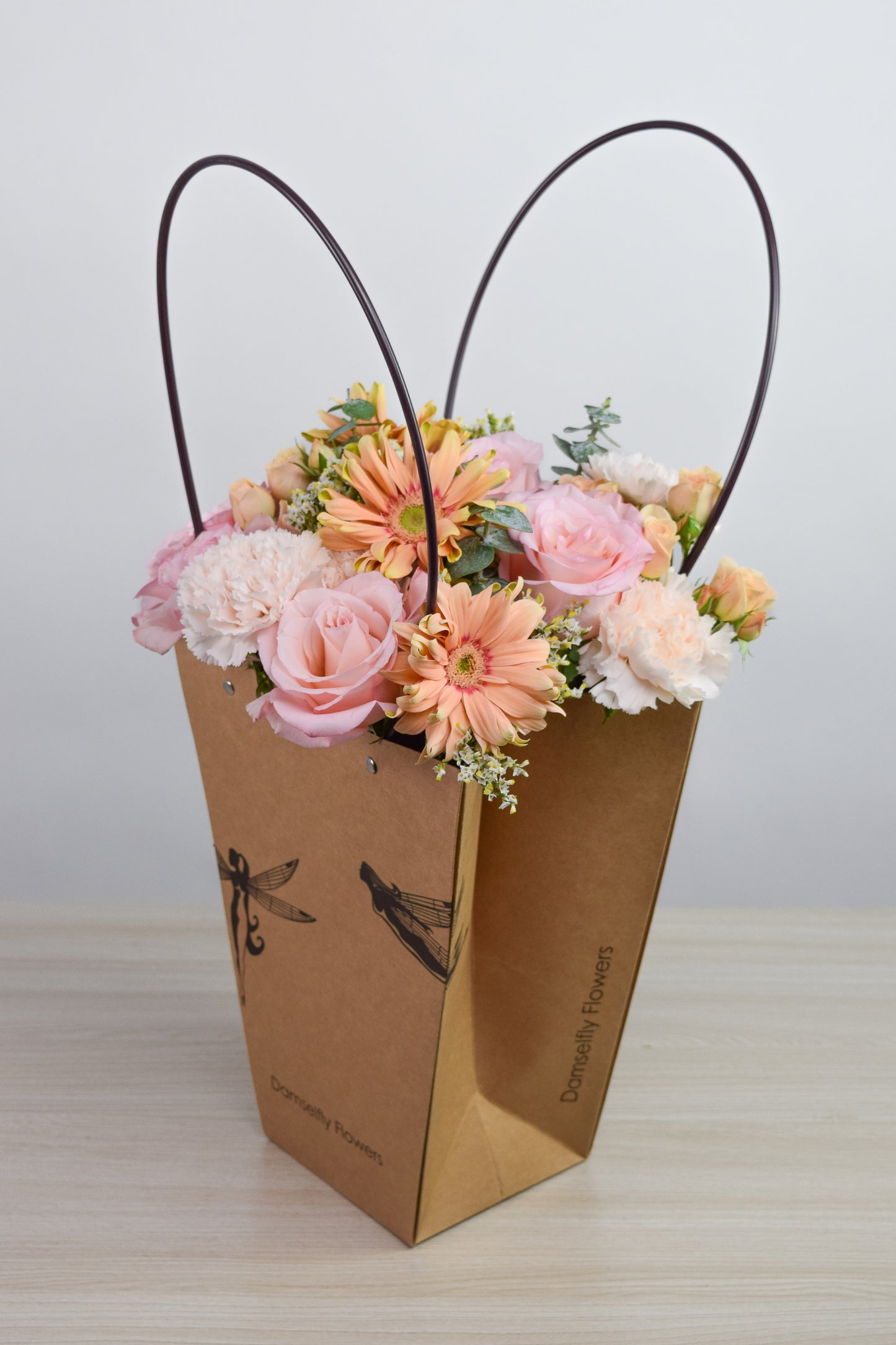 Floral arrangement in a Damselfly Flowers branded gift bag with white background