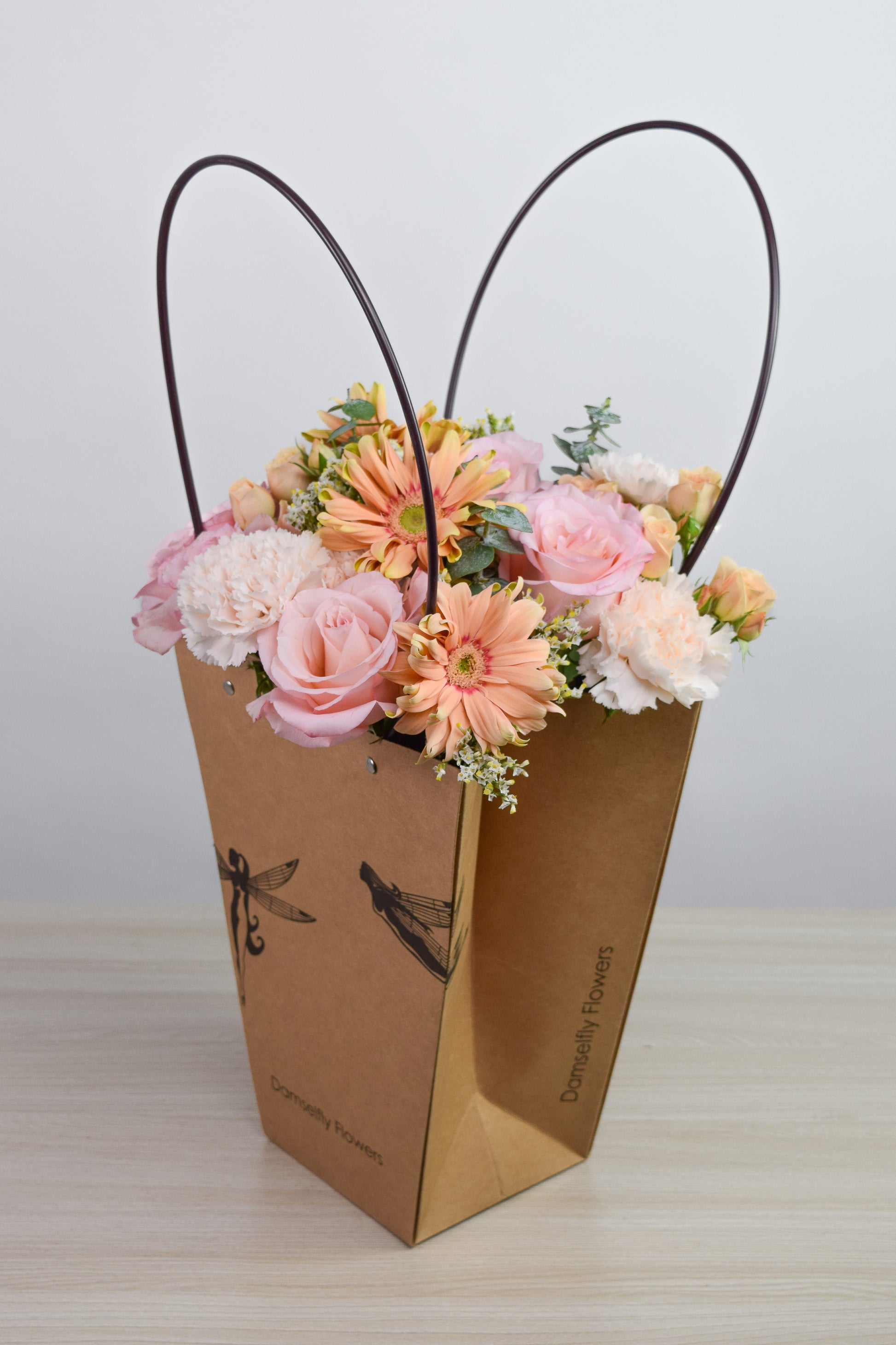 Floral arrangement in a Damselfly Flowers branded gift bag with white background