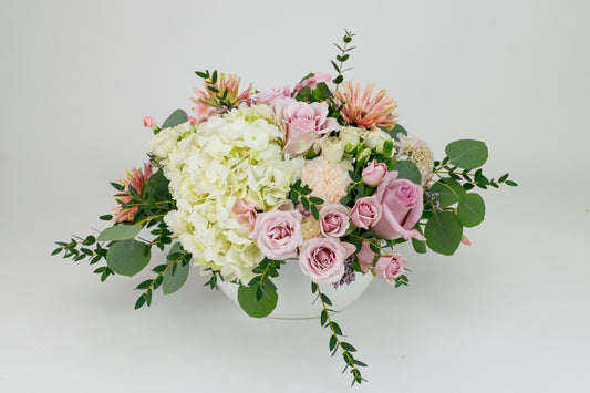 Floral arrangement with pink and white flowers in a white vase on a light background