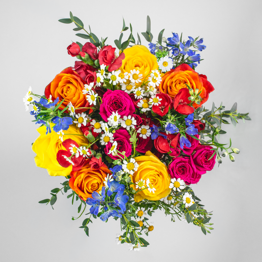 Colorful bouquet of flowers including roses and daisies on a light gray background